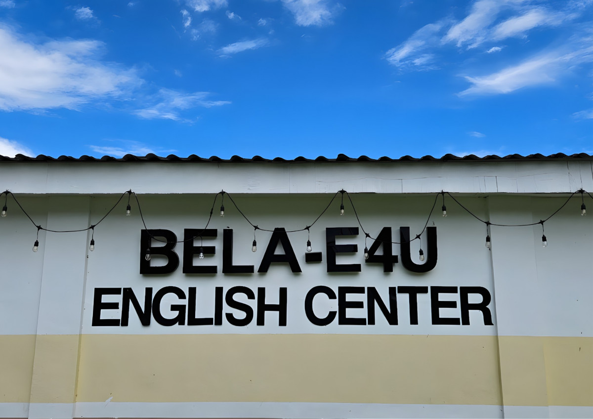 克拉克 BELA 語言學校校舍外牆,白牆上寫著黑色大字 BELA-E4U ENGLISH CENTER,屋簷下掛著一串燈泡