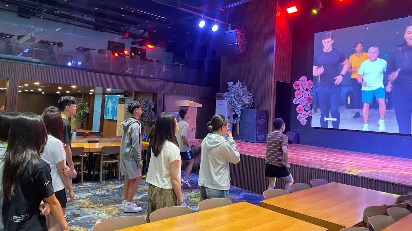 獨立營學員在 QQCafe 舞台前跟著大螢幕影片跳舞(往年營隊)