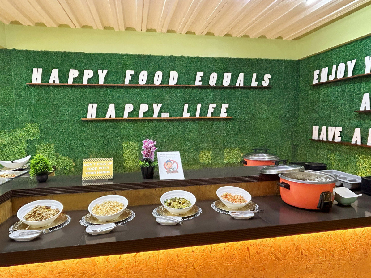 宿霧 CG SPARTA 校區餐廳的自助菜檯,擺著四道菜和電鍋,牆上寫著 Happy Food Equals Happy Life