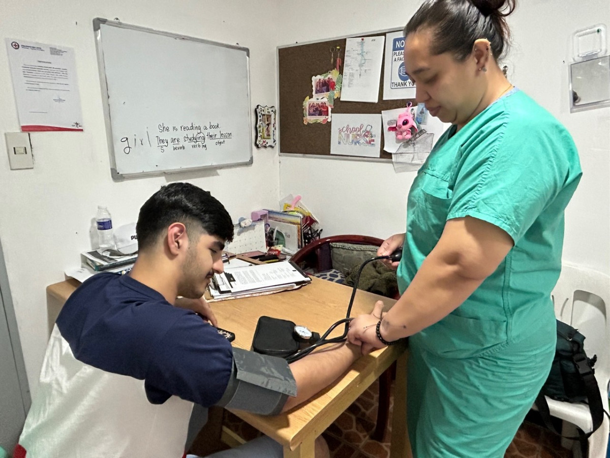 克拉克 GS 語言學校的醫務室,穿綠色制服的校護幫學生量血壓,後面牆上有白板和軟木公告板